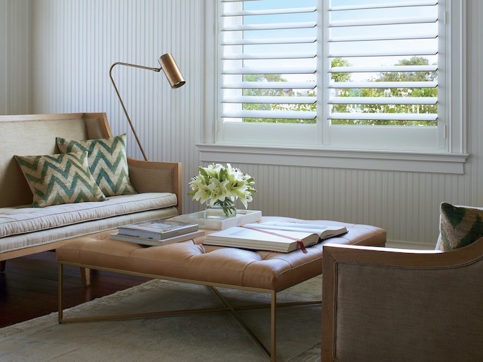 A living room coffee table with flowers in a round vase and a rectangular tray and books.